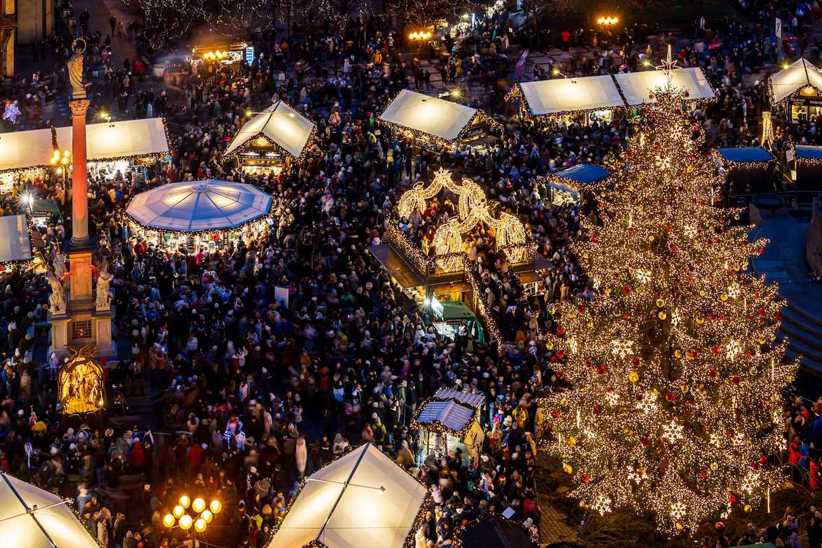 Beleuchteter Weihnachtsmarkt mit Ständen und Weihnachtsbaum am Abend